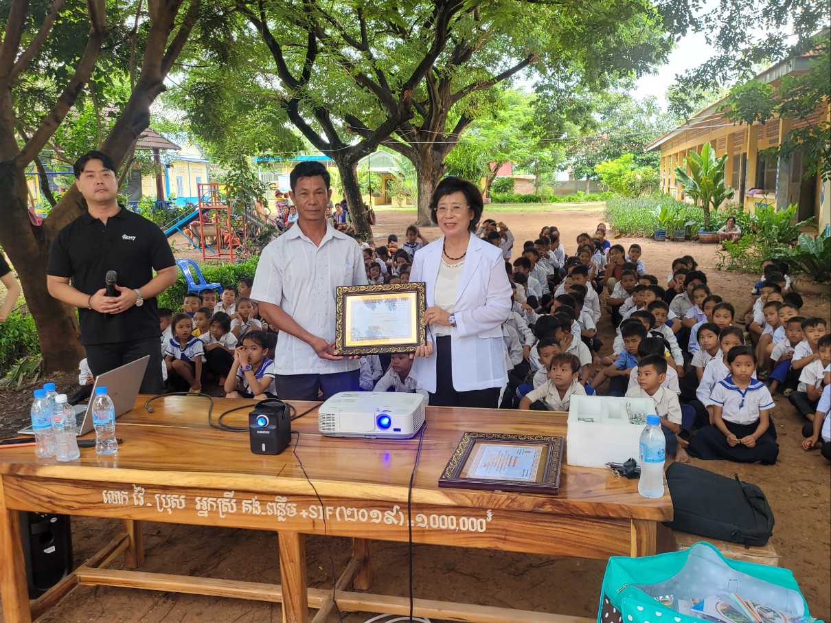 캄보디아 슈어초등학교 교장 체이 폰버롬에게 컴퓨터 등 교육기자재를 전달하는 서사라 목사.