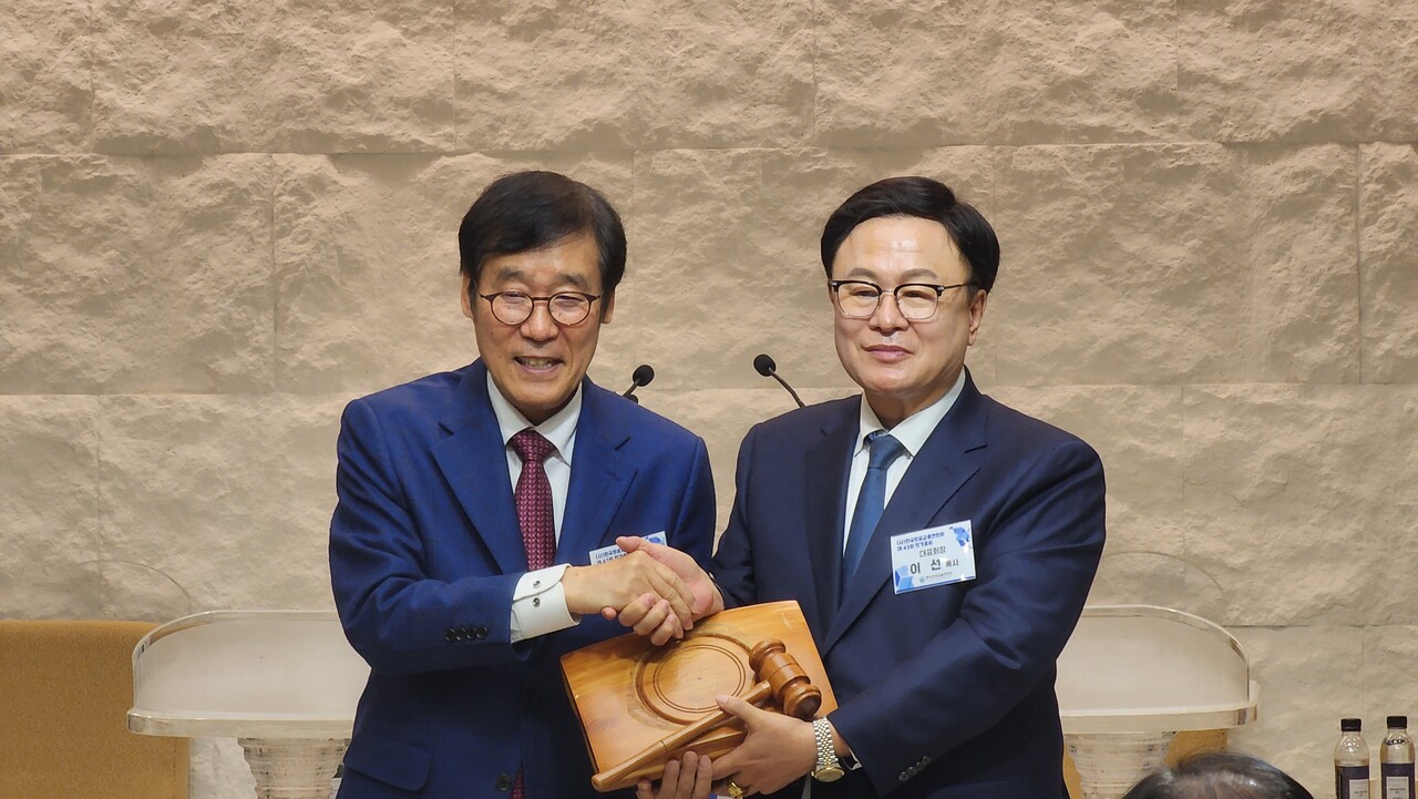 직전 대표회장 권순웅 목사에게 의사봉을 전달 받는 신임 대표회장 이선 목사(오른쪽).